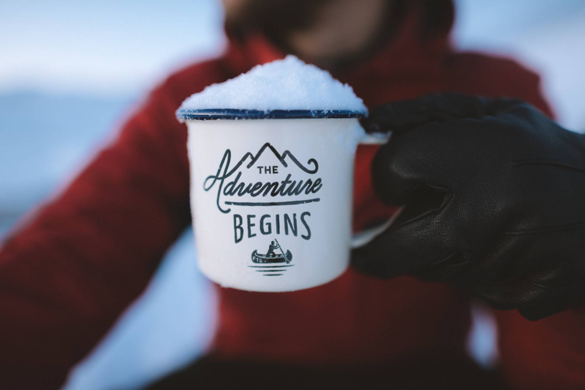 Mug with snow on top that looks like a mountain peak and the mug states The Adventure Begins